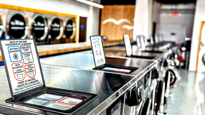 Row of Dexter washer top decks in a laundromat with stack dryers along the back wall